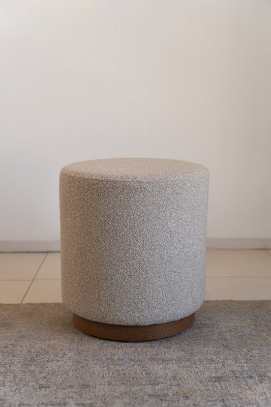 הדום עגול מבד בוקלה בצבע שמנת עם בסיס עץ טבעי.