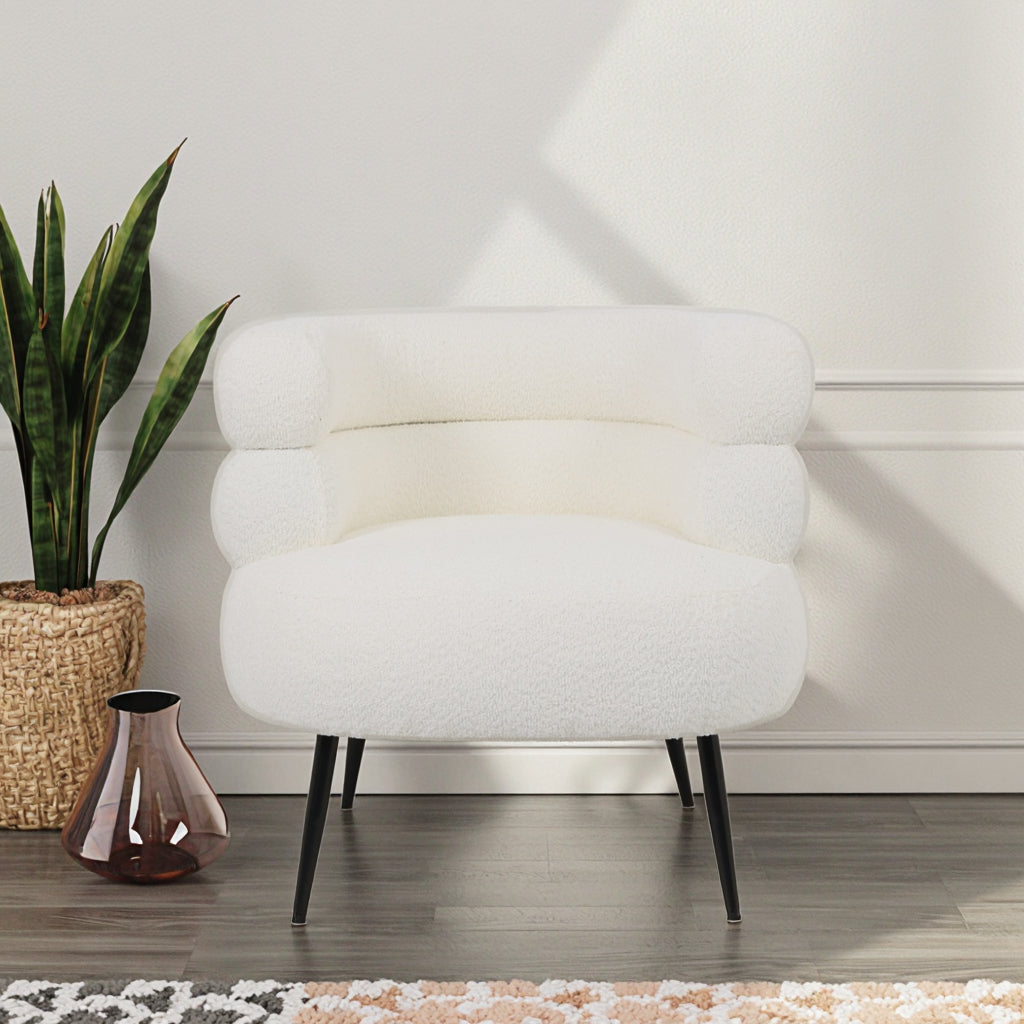 כורסה Velia עם רגלי מתכת שחורות וריפוד בוקלה לבן בפינת קריאה אלגנטית ומוארת