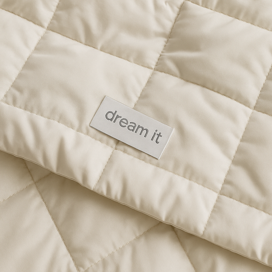 קלוז־אפ של שמיכת חורף לבנה מבד מיקרופייבר עבה עם תפרים מרובעים ולוגו DREAM IT בגוון אפור – מדגיש את איכות החומר והעיצוב האלגנטי.