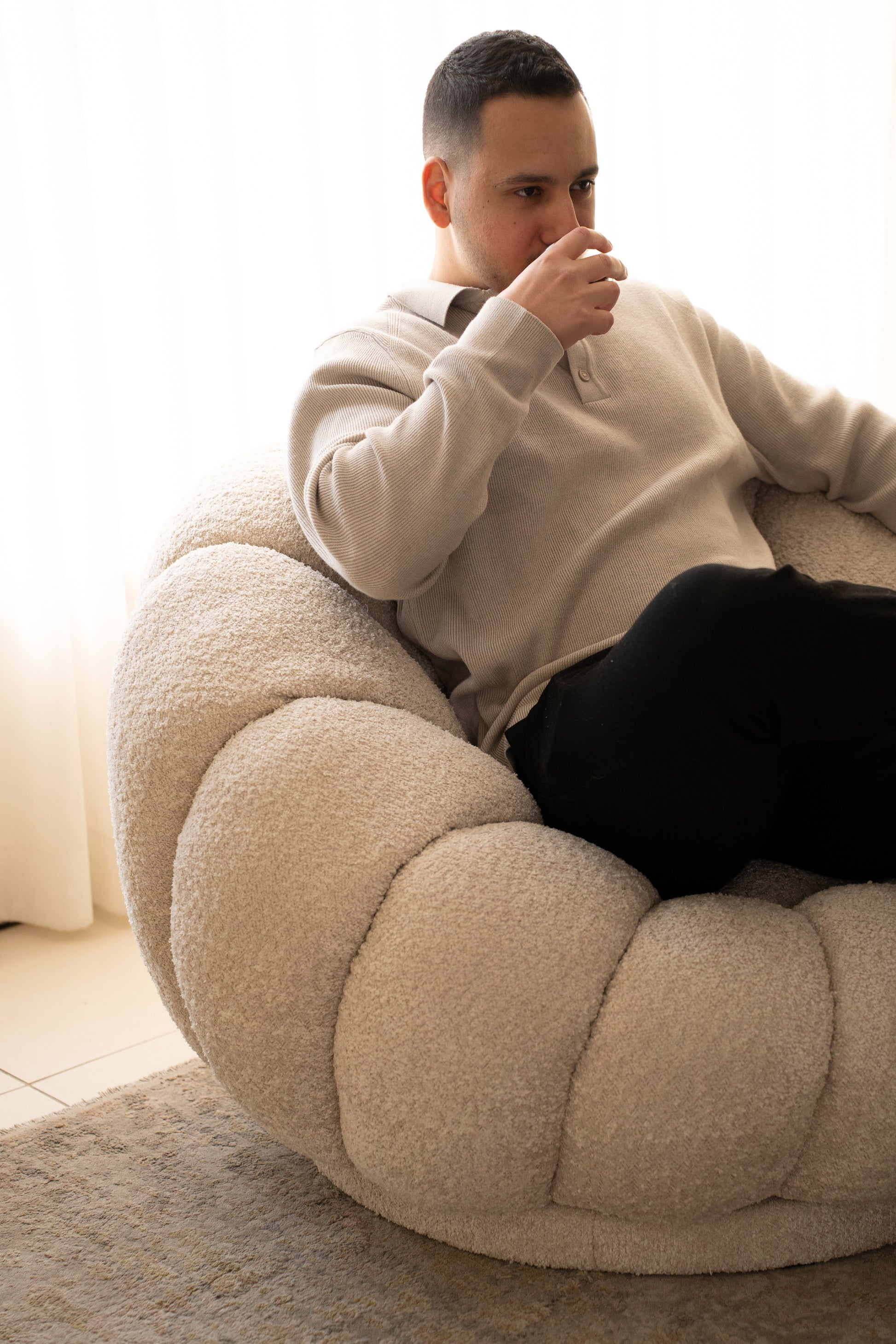 כורסה בוקלה מסתובבת דגם Flower עם אדם שותה קפה