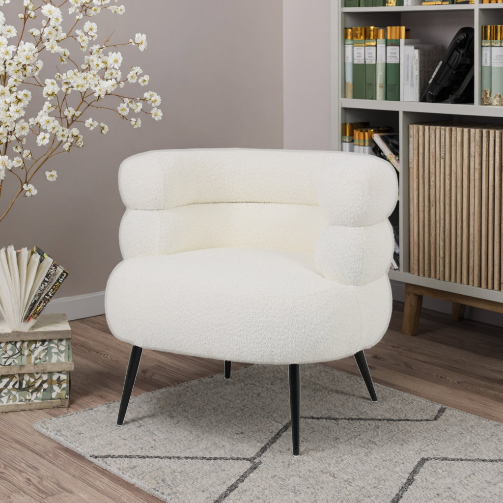 כורסה Velia מבית DreamIt – ריפוד בוקלה בגוון לבן שמנת בחלל סלון מודרני עם ספרייה ועיצוב טבעי
