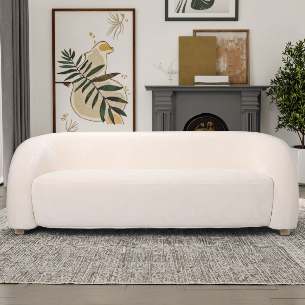 ספה Olivia בגוון שמנת לצד קיר אמנות וצמחים