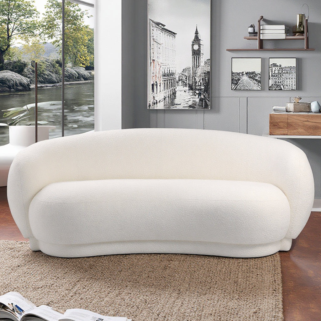 ספת Amara לבנה מבד בוקלה בעיצוב אלגנטי ורך בחלל סקנדינבי עם נוף ירוק בחוץ