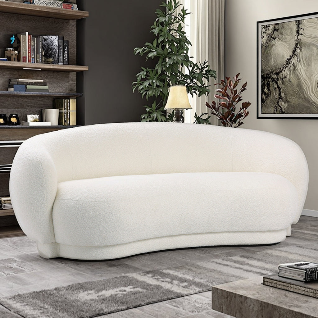 ספת Amara לבנה מבד בוקלה בעיצוב עגלגל ויוקרתי לצד ספרייה וצמחיה בסלון מודרני